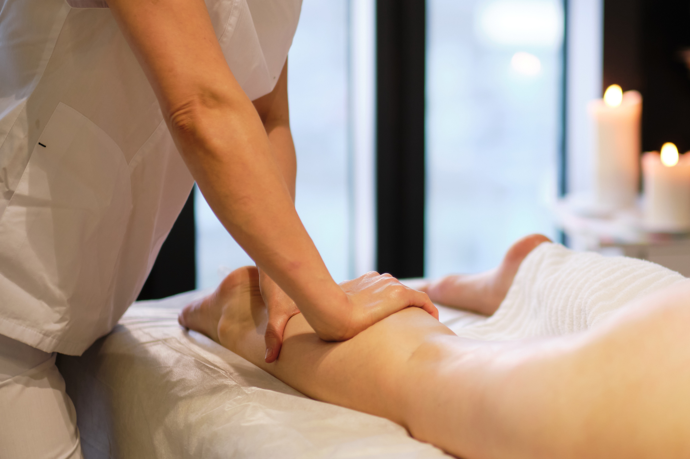 Detail of hands massaging human calf muscle.Therapist applying pressure on female leg. Hands of massage therapist massaging legs of young woman in spa salon. Body care in spa salon for young woman